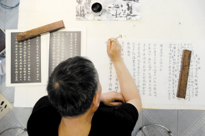 冉隆泉在练字，在雕刻极小的字时自己是看不见的，全靠平时练习书法的手感。